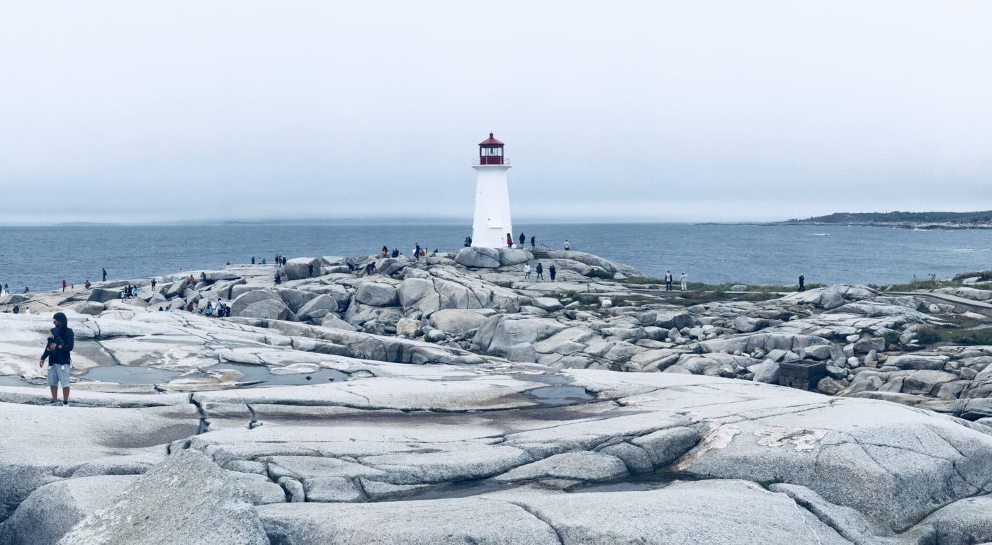 Wide view of Peggy’s Point Lighthouse across the granite shoreline