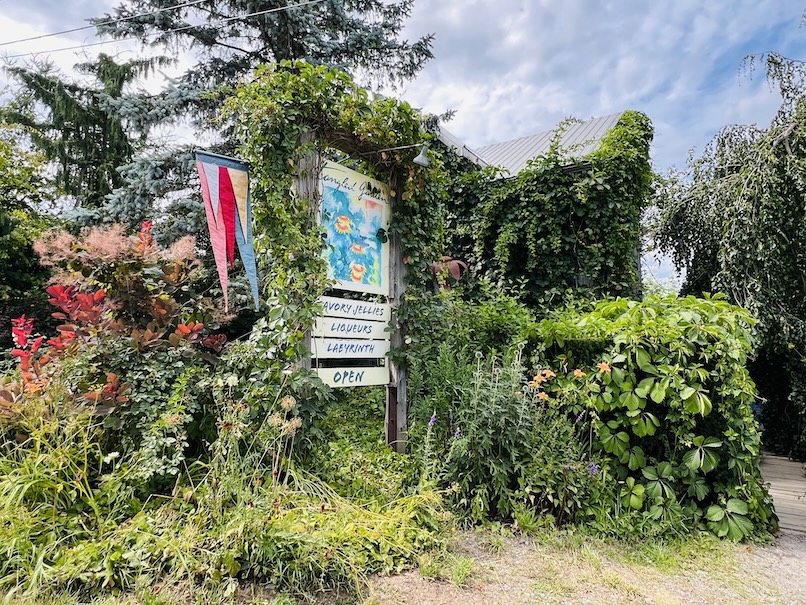 Entrance to Tangled Garden in Grand Pré, Nova Scotia, surrounded by lush greenery